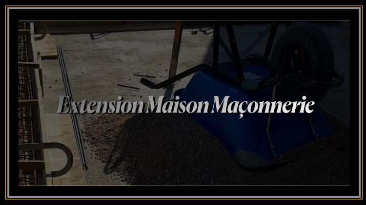 Chantier d'extension de maison en maçonnerie avec une brouette bleue sur un tas de sable et ferraillage de fondation.